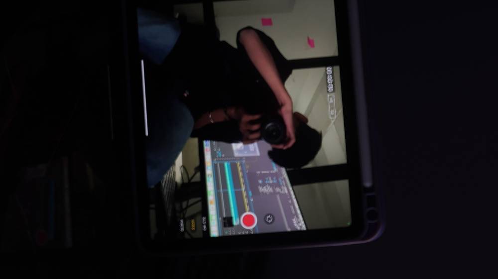 Shiv filming in the office studio with a camera and editing timeline on screen