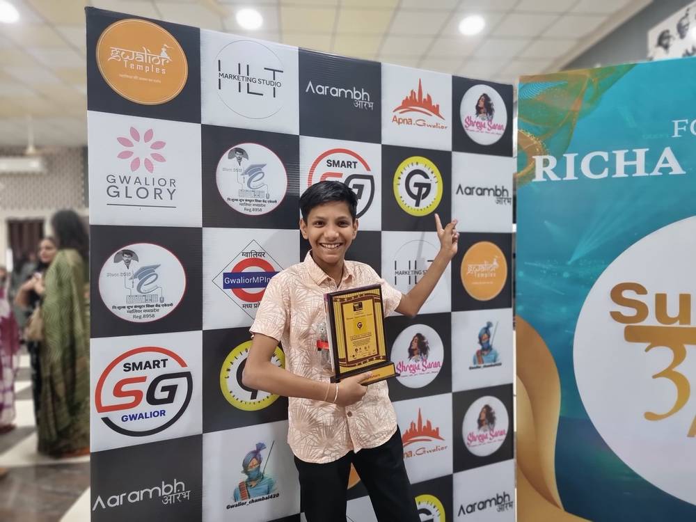 Shiv holding the Graphic Partner trophy in front of the Season 3 partner wall